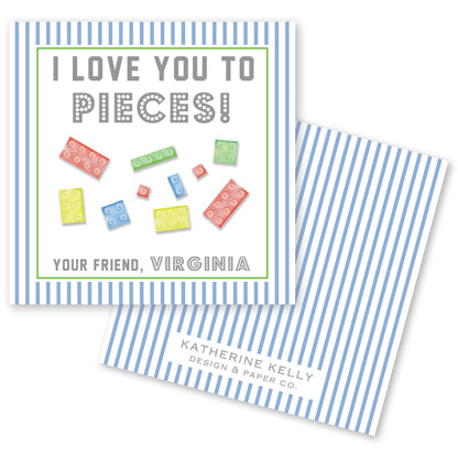 The image is a greeting card with a blue and white striped background. The card features a message that reads "I LOVE YOU TO PIECES!" and includes illustrations of various colored Lego bricks. The card also includes text that says "Your Friend, Virginia" and "Katherine Kelly Design & Paper Co."