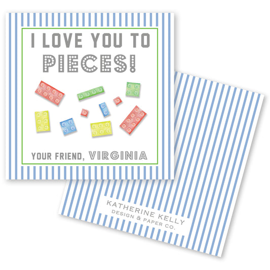 The image is a greeting card with a blue and white striped background. The card features a message that reads "I LOVE YOU TO PIECES!" and includes illustrations of various colored Lego bricks. The card also includes text that says "Your Friend, Virginia" and "Katherine Kelly Design & Paper Co."