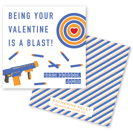 The image is a Valentine's Day card with a playful design featuring a Nerf gun and a target with a heart. The text on the card reads "Being your Valentine is a blast!" and "Your friend, James".
