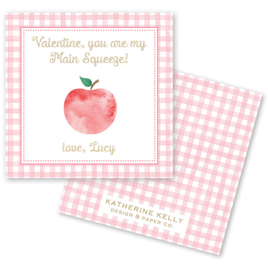The image is a Valentine's Day card with a pink and white checkered background. The card features a watercolor illustration of an apple and a message that reads "Valentine, you are my Main Squeeze!" The card also includes a name tag that says "love, Lucy".