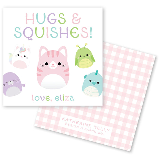The image is a greeting card featuring a pink cat surrounded by various colorful animal characters, including a unicorn, a dragon, and a cat. The text on the card reads "HUGS & SQUISHES!" and "love, eliza".