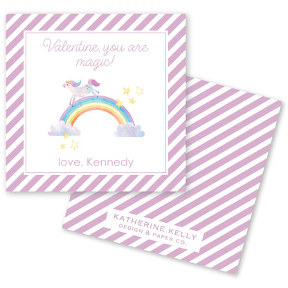 The image is a Valentine's Day card with a unicorn riding a rainbow and stars. The card has a pink and white striped background and a message that reads "Valentine, you are magic!" The card also includes a name, "love, Kennedy", and a logo for "KATHERINE KELLY DESIGN & PAPER CO."