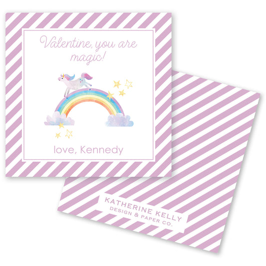 The image is a Valentine's Day card with a unicorn riding a rainbow and stars. The card has a pink and white striped background and a message that reads "Valentine, you are magic!" The card also includes a name, "love, Kennedy", and a logo for "KATHERINE KELLY DESIGN & PAPER CO."