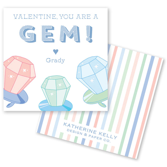 The image is a Valentine's Day card featuring a playful design with three colorful gem-like objects, each with a heart symbol, and the text "Valentine, you are a GEM! Grady" along with the company name "KATHERINE KELLY DESIGN & PAPER CO."